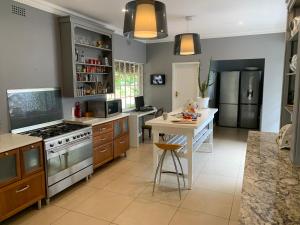 eine Küche mit Küchengeräten aus Edelstahl und einem weißen Tisch in der Unterkunft Nine Loch Guesthouse in Johannesburg