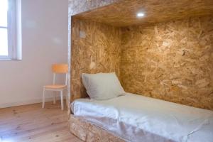 Cama en habitación con pared de piedra en Patinha Inn, en Évora