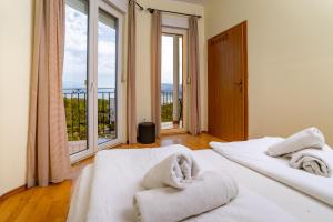 two white beds in a room with large windows at Salvija Apartments in Lopar