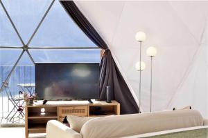 a living room with a large screen tv in a tent at Vi Naturae Glamping in Fajã da Ovelha