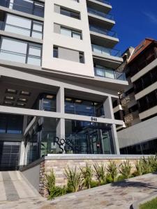 a large white building with glass windows at Residencias Roque Suarez in Mar del Plata