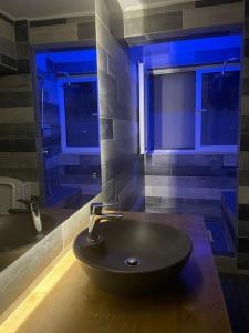 baño con lavabo negro y luces azules en The Beehive en Mitilene