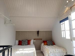 サアラ・デ・ロス・アトゥネスにあるZahara Beach Houseの白い壁と窓が備わる客室で、ベッド2台が備わります。