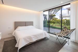 a bedroom with a bed and a chair and a large window at Vale do Lobo Sky Villa by Homing in Vale do Lobo