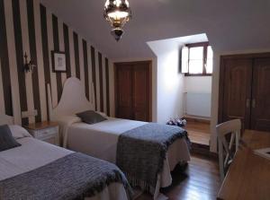 um quarto de hotel com duas camas e uma mesa em HOTEL RURAL OSCOS em Villanueva de Oscos
