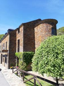 een bakstenen gebouw met een struik ervoor bij HOTEL RURAL OSCOS in Villanueva de Oscos