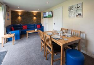 een woonkamer met een tafel en een blauwe bank bij Sandy Glade Holiday Park in Burnham on Sea