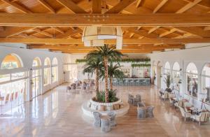 a large lobby with chairs and a palm tree in the middle at Ilunion Sancti Petri in Chiclana de la Frontera