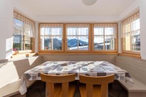 a dining room with a table and some windows at Casa Freina in Vigo di Fassa