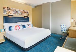 a bedroom with a white bed and a desk and a chair at Aloft Louisville Downtown in Louisville