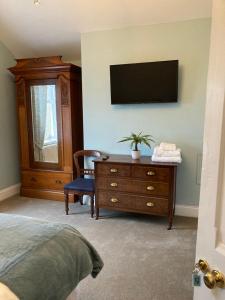 a bedroom with a dresser and a television on a wall at The Old Lodge Guest House in Lincoln
