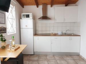 uma cozinha com armários brancos e um frigorífico branco em El Caramelito 1 em Maspalomas