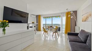 uma sala de estar com televisão e uma mesa com cadeiras em Cannes Marina Appart Hotel Mandelieu em Mandelieu-la-Napoule