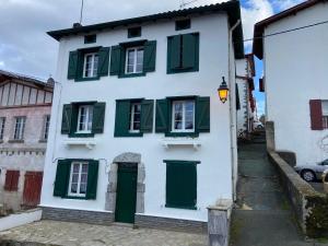 a white house with green shutters on a street at Studio Centre Ville in Cambo-les-Bains