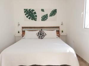 una camera bianca con un grande letto con lenzuola bianche di El Caramelito 1 a Maspalomas