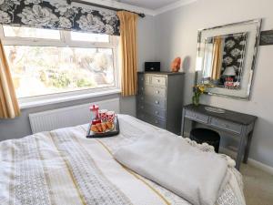 een slaapkamer met een bed, een bureau en een spiegel bij 1 Gloucester Way in Pembroke Dock