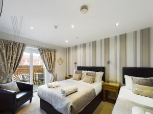a bedroom with two beds and a chair at Sandbanks Suite in Blackpool