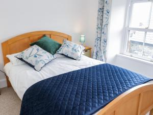 ein Schlafzimmer mit einem Bett mit einer blauen Bettdecke und Kissen in der Unterkunft Dolwen in Betws-y-coed
