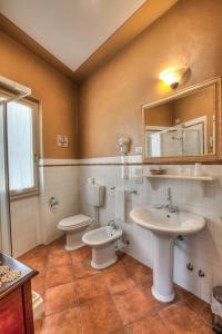 bagno con 2 servizi igienici, lavandino e specchio di Hotel Locanda Degli Artisti a Borgo San Lorenzo