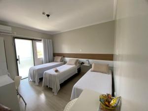 um quarto de hotel com duas camas e uma mesa em Faixa Hotel em Vitória da Conquista