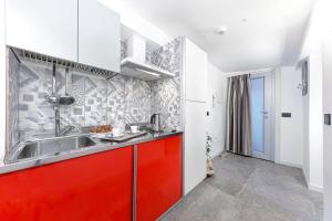 una cucina con armadi rossi e un lavandino rosso di Mini Suite (3 adulti) a Riccione