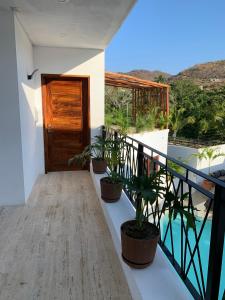 uma varanda com vasos de plantas e uma porta de madeira em Luana suites- Suite Nikté em Zihuatanejo