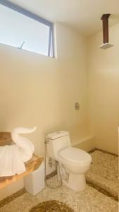 a bathroom with a white toilet and a window at Luana suites- Suite Nikté in Zihuatanejo