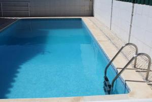 ein Swimmingpool mit blauem Wasser in einem Gebäude in der Unterkunft Villaricardo_azeitao Moradia moderna para 9 guests in Azeitão