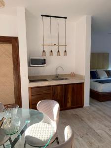 een keuken met een glazen tafel en stoelen en een bed bij Luana suites- Suite Nikté in Zihuatanejo