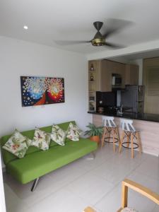 a living room with a green couch and a kitchen at Espectacular y cómodo Apartamento en Girardot WiFi in Girardot
