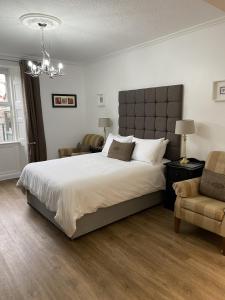 a bedroom with a large bed and a chair at The Roxburgh Guest Accommodation in Berwick-Upon-Tweed