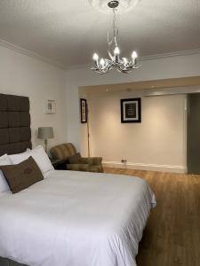 a bedroom with a large white bed and a chandelier at The Roxburgh Guest Accommodation in Berwick-Upon-Tweed