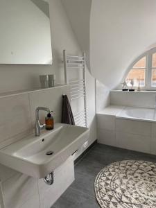 a white bathroom with a sink and a rug at Ferienhaus Fischerhuus in Zirchow