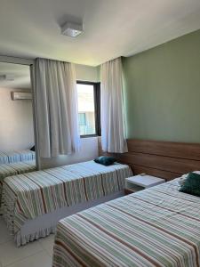 a hotel room with two beds and a mirror at ILOA RESORT - Barra de São Miguel in Barra de São Miguel