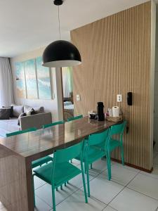 a dining table with green chairs in a living room at ILOA RESORT - Barra de São Miguel in Barra de São Miguel