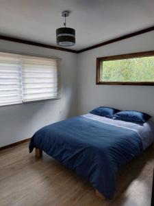a bedroom with a bed with blue sheets and a window at Villarrica Pucón Aldea Molco in Villarrica