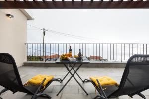 einen Tisch mit 2 Stühlen und Flaschen Wein auf dem Balkon in der Unterkunft Referta House in Prazeres