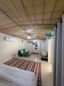Al WāşilにあるAl Khamail Land for Greenhostelのベッド1台、ソファ、ラグが備わる客室です。