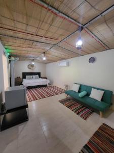 a living room with a green couch and a bed at Al Khamail Land for Greenhostel in Al Wāşil