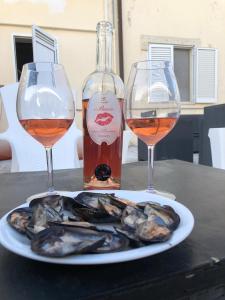 two wine glasses and a plate of mussels on a table at La Masseria Hotel Ristorante Centro Benessere in Cocumola