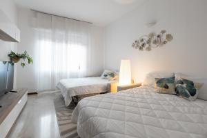 a white bedroom with two beds and a window at San Siro Big House Wifi Netflix Free Parking in Milan