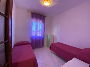 een kamer met 2 bedden en een raam met paarse lakens bij FURLE - 6 posti letto in zona centrale in San Vincenzo