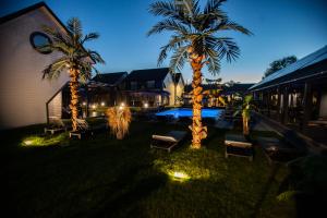 dwie palmy i ławki na dziedzińcu w nocy w obiekcie Royal Palm Mielno w mieście Mielno
