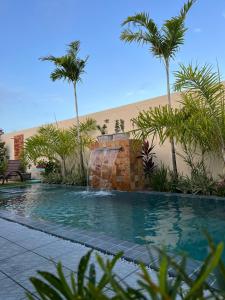 einen Pool mit einem Wasserfall und Palmen in der Unterkunft Casa de Temporada - Barra de São Miguel in Barra de São Miguel