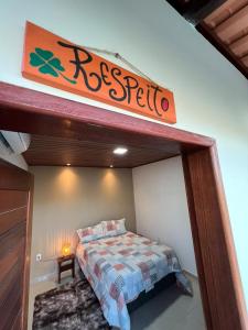 1 dormitorio con 1 cama y un cartel en la pared en Casa de Temporada - Barra de São Miguel en Barra de São Miguel