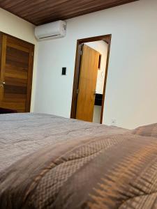 1 dormitorio con 1 cama y puerta de madera en Casa de Temporada - Barra de São Miguel, en Barra de São Miguel