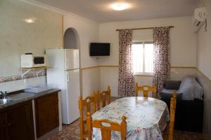eine Küche mit einem Tisch und einem Kühlschrank sowie einem Tisch und Stühlen in der Unterkunft Apartamentos Bellavista Bolonia in Bolonia