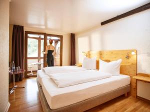 a woman standing in a hotel room with a bed at Weinhaus Lenz in Briedern