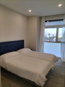 two beds in a bedroom with a large window at Apartamentos Kai Santurtzi in Santurce