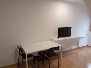 een witte tafel met stoelen en een tv aan de muur bij Loft nuevo in Pontevedra